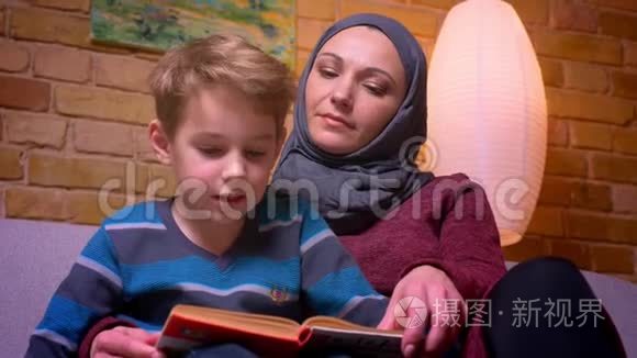 特写镜头集中的小男孩和他的母亲在头巾学习如何阅读在家里专心。