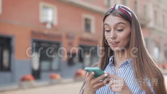 年轻漂亮的白种人女孩，有棕色头发和头巾，穿着带条纹，使用她的智能手机。 妇女