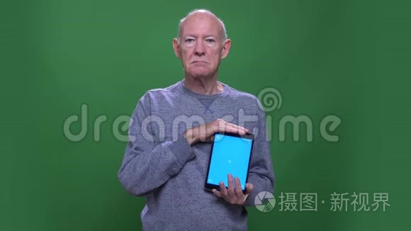 用平板电脑拍摄老白种人的特写镜头，用蓝色屏幕观看背景摄像机