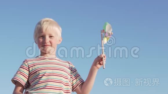 金发男孩在慢动作地玩风车公园视频