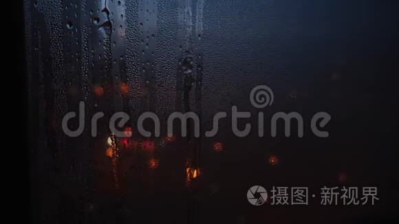 晚上，雨滴落在玻璃上的特写和透过窗户模糊的光点。 概念