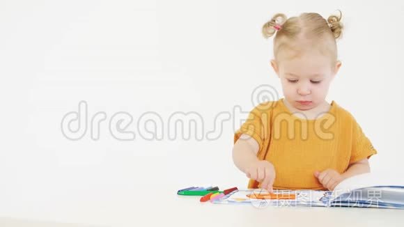 金发婴儿用黄色蜡笔着色未知的图片