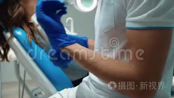 戴着医疗手套和戴着眼镜的年轻牙医准备检查年轻的黑发女人病人调整他的身体