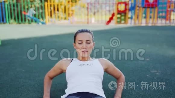 运动女性在新鲜空气中对腹肌进行锻炼。 那个女孩在街上参加体育活动。