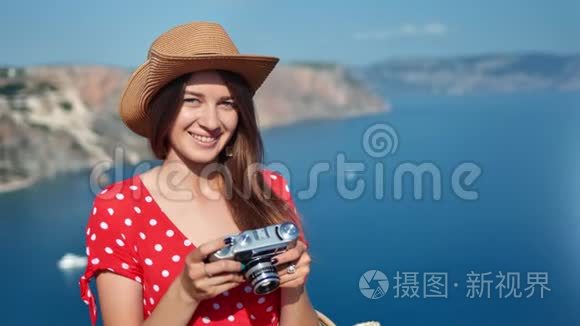 阳光明媚的夏日，美丽的旅行女性戴着帽子，手持相机拍摄海上风景