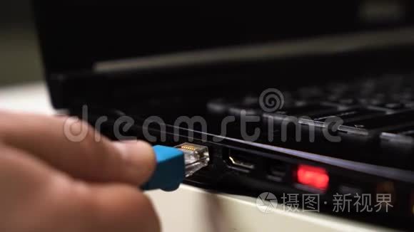 特写男性手连接蓝色以太网电缆笔记本电脑与发光的红色usb端口。