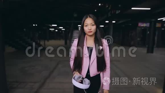 亚洲女人晚上戴着耳机在地下行走