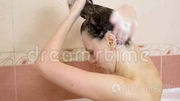 裸体的黑发女人在坐在浴室的头发上放洗发水。 特写的头和肩膀..