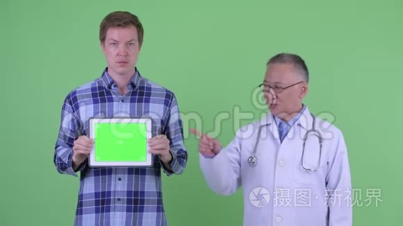 快乐成熟的日本男医生，年轻男子展示数码平板电脑，竖起大拇指