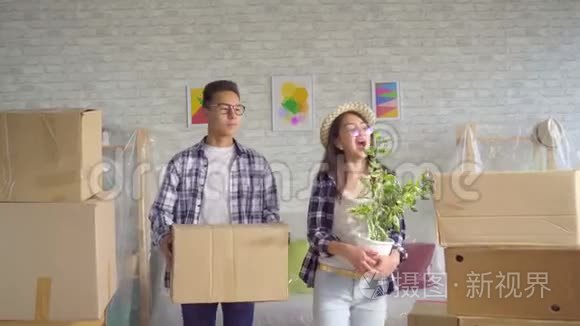 积极的亚洲年轻夫妇手里拿着箱子搬进了新公寓
