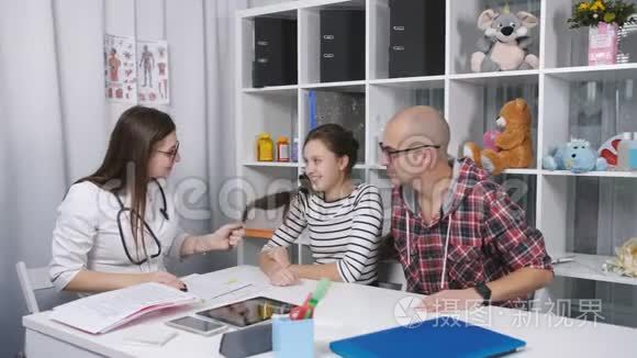 4友好的医生在办公室里和父亲和孩子的病人交谈。