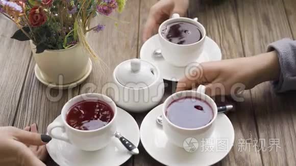 在现代咖啡馆里，三个女人在碗附近端着一杯茶，桌上放着糖。 放松一下