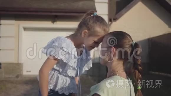 肖像小可爱女孩和妈妈站在后院户外。 关系妈妈和女儿。 真正幸福的家庭