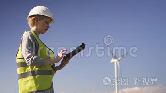 技师站在风力机附近，为平板电脑做笔记