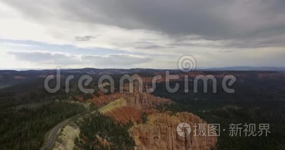 空中摄像机在峡谷上空移动，底部有一片松树林和蜿蜒的公路