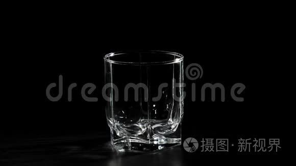 豪华威士忌。 空玻璃在黑色背景下旋转在黑色桌子上。 准备饮酒。 不倒翁威士忌。