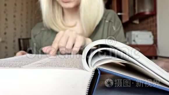 一个模糊的、面目全非的金发女人在翻阅一本大书，一根手指在书页上