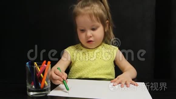 小女孩用绿色铅笔在纸上画画