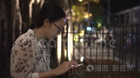 在游客座位区使用免费无线网络连接智能手机的戴眼镜的亚洲妇女