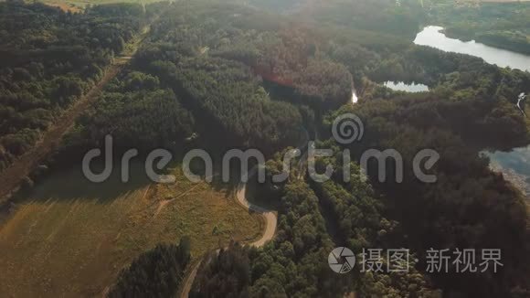 在一个明亮的夏日和接下来的一条道路上，旋转空中全景景观视频的几个被森林包围的湖泊