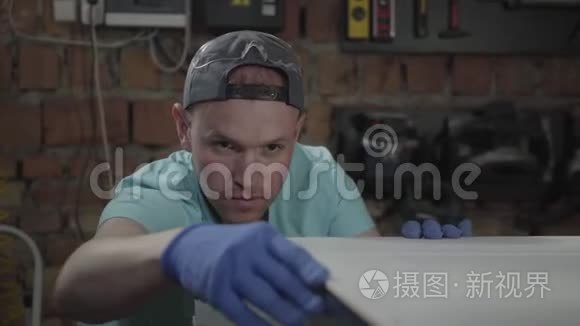 帽中集中的人的肖像，参与他的工作。 戴手套的工人检查和测量他的DIY