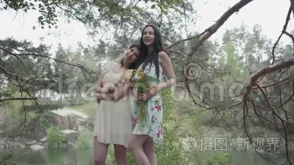 两个穿着短夏装的可爱的年轻女子站在岩石上，开着野花，望着森林