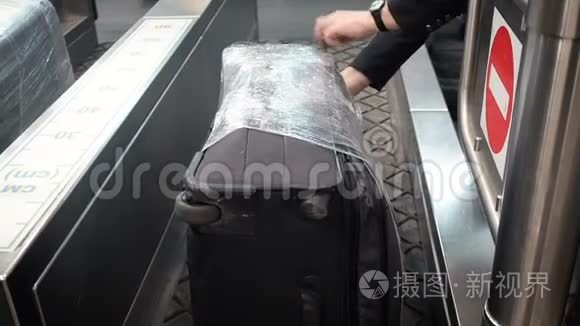 贴在行李标签上的特写镜头，附在机场的红色塑料手提箱上。 员工将行李标签贴在