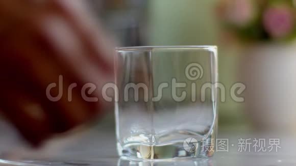 一个人从一个透明的水壶里倒水到水玻璃里