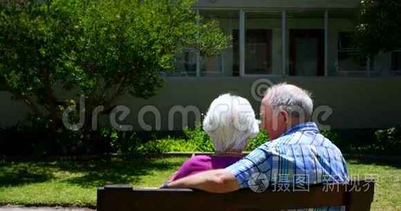 活跃的高加索老夫妇在养老院花园观看相册的后景