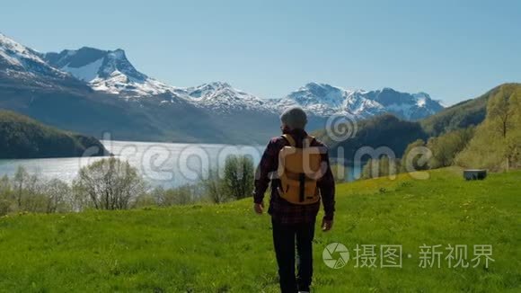 旅行者走在绿草如茵的小山上，有着令人叹为观止的挪威山景