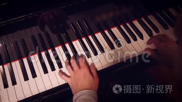 钢琴演奏者在钢琴上用低光线和肩部视野演奏一首歌