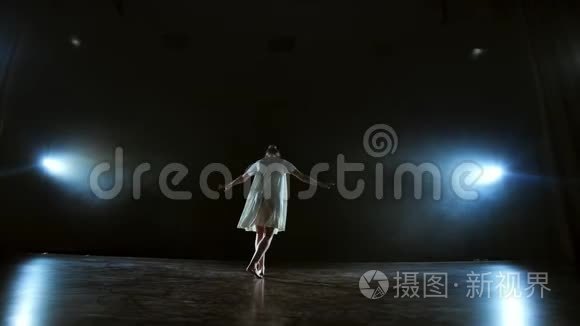 变焦相机在舞台上移动与软件和烟雾。 穿着白色裙子旋转塑料舞的女孩芭蕾舞演员