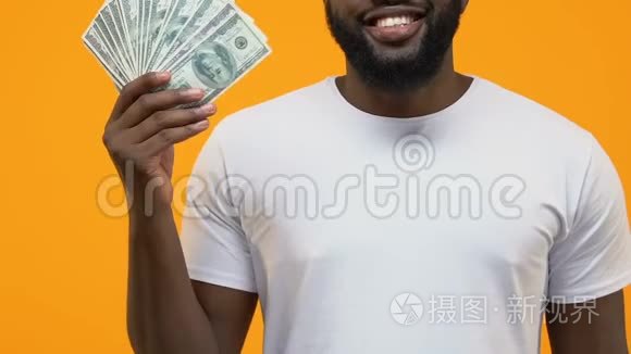 快乐的非洲男性手里拿着美元钞票，财务成功，投资
