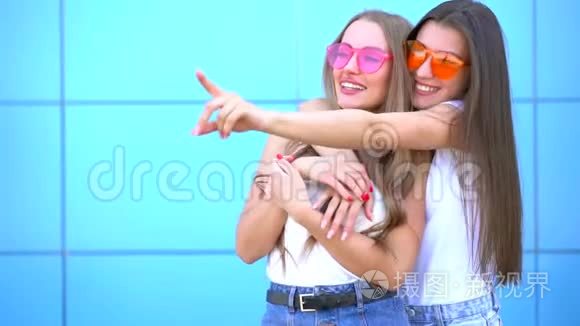 两个年轻的时髦女人在蓝墙上笑视频