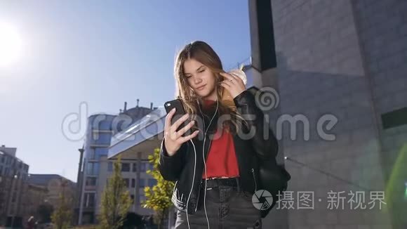 年轻貌美的女士，戴着长发耳机，在城市街头散步时使用智能手机