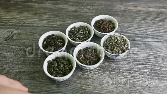 人的手拿着一个个小器皿，里面有各式各样的茶叶