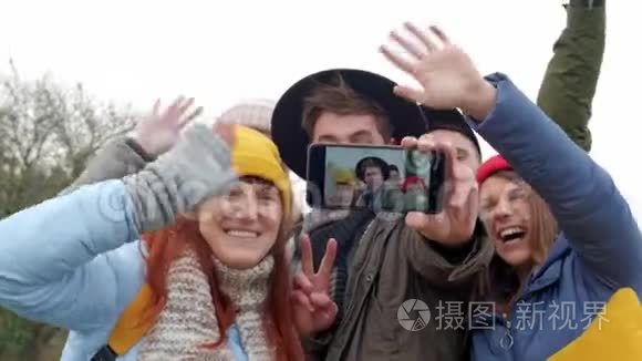 一群年轻的时髦朋友用智能手机相机自拍。 秋天森林的背景