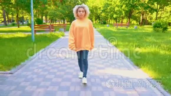 穿黄色毛衣的女孩在公园里散步视频