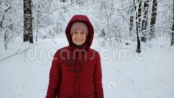 微笑的女人走在白雪覆盖的森林里，享受冬天的自然，放松