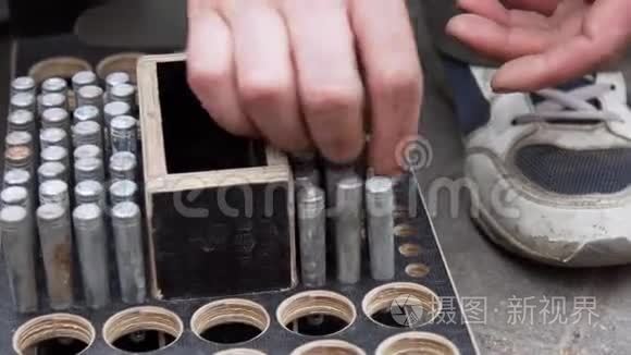 工人`手把圆筒状的金属别针放进有圆孔的木箱里。
