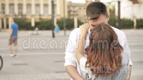 一对深情的年轻夫妇拥抱并分享一个浪漫的吻，同时站在城市的一条街上