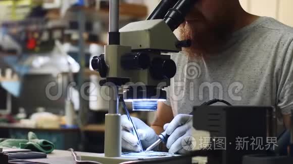修理工通过显微镜观察设备电路板上的焊料。