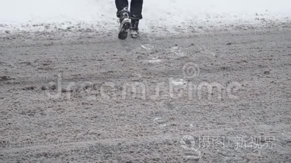 行人`的双腿在冬季降雪时在白天缓慢地穿过一条雪道。 交通恶劣的天气条件