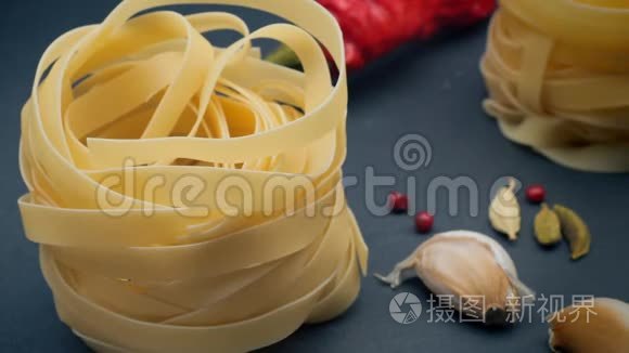 4K视频。 意大利面用香料在灰色背景上筑巢的fettuccine辣椒，茴香种子和辣椒.. 游泳和游泳