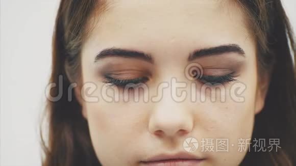 可爱的年轻女性的脸向下看,然后用蓝色的大眼睛看着相机,然后再往下看