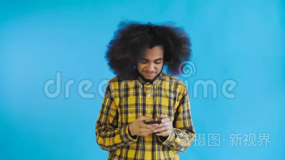 非洲裔美国人的肖像，卷发，在蓝色背景下的智能手机上聊天。 情感概念