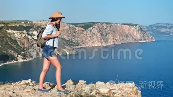 美丽的嬉皮士徒步旅行的女人背着背包走在山顶欣赏令人惊叹的海景