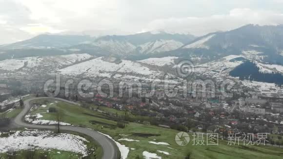 在多云天气下冬季在山区飞行.. 城市在群山和绿草中