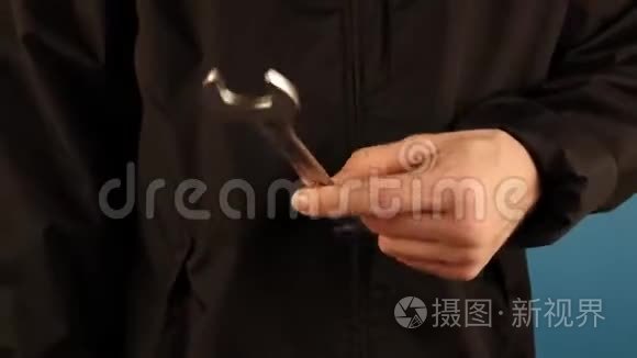 一个穿黑色衣服的人手里拿着一把扳手，放在蓝色的背景上