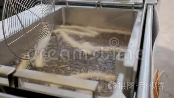 厨师在油炸机里搅拌沸腾的油视频